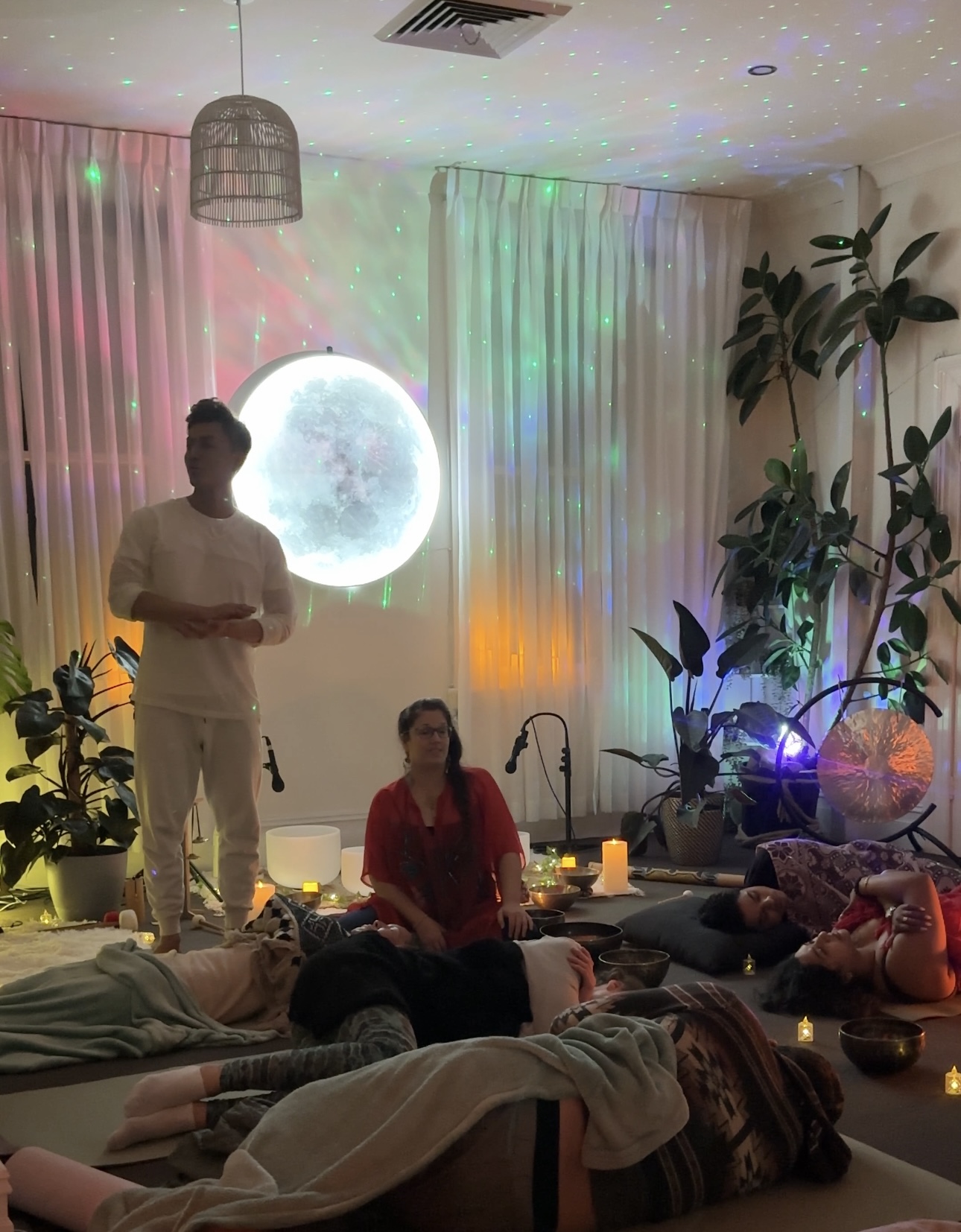 Phoenix and Katrina Noela holding a somatic sound event under the Mystic moon wall
